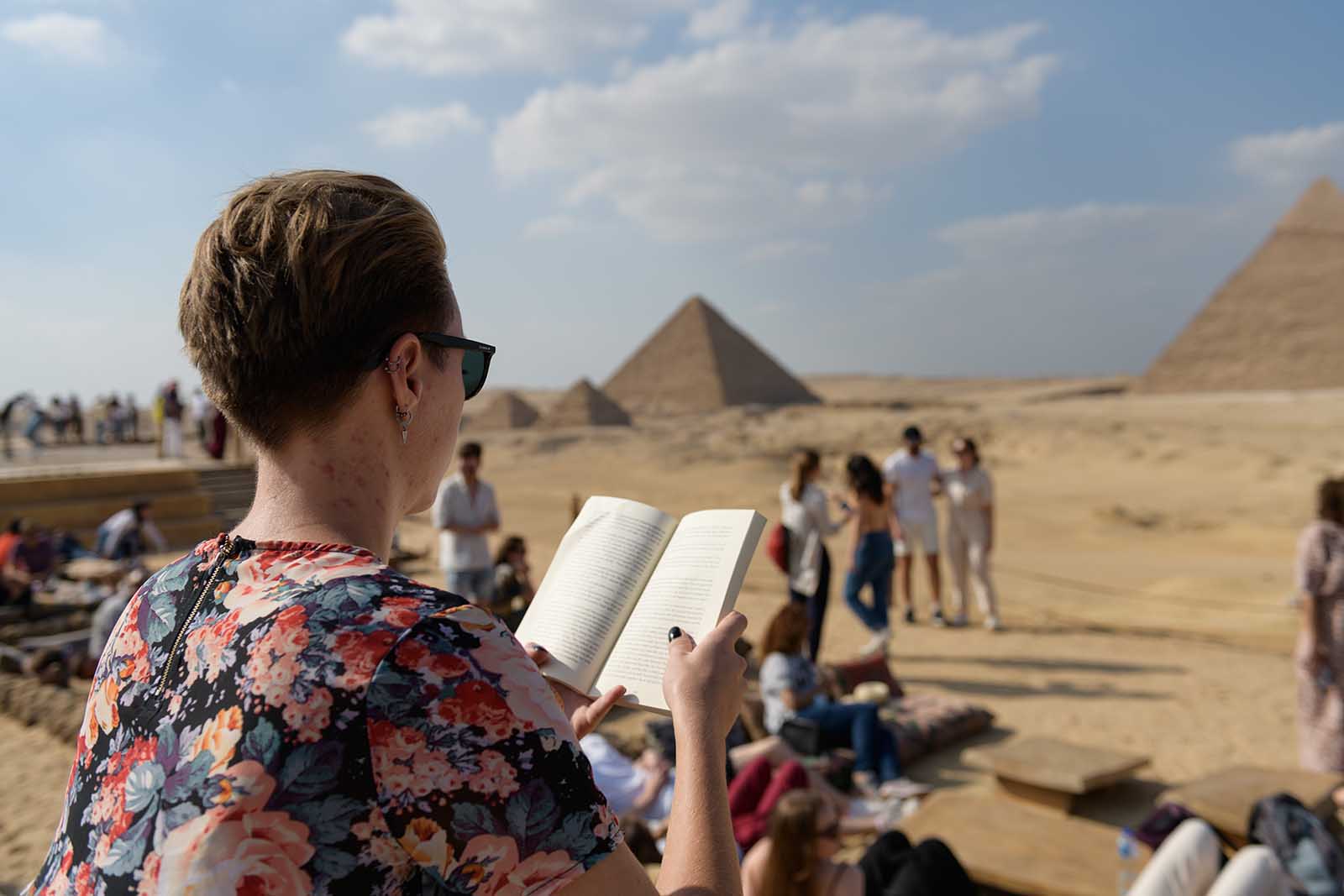 female student reading about the pyramids of Giza at archeological site