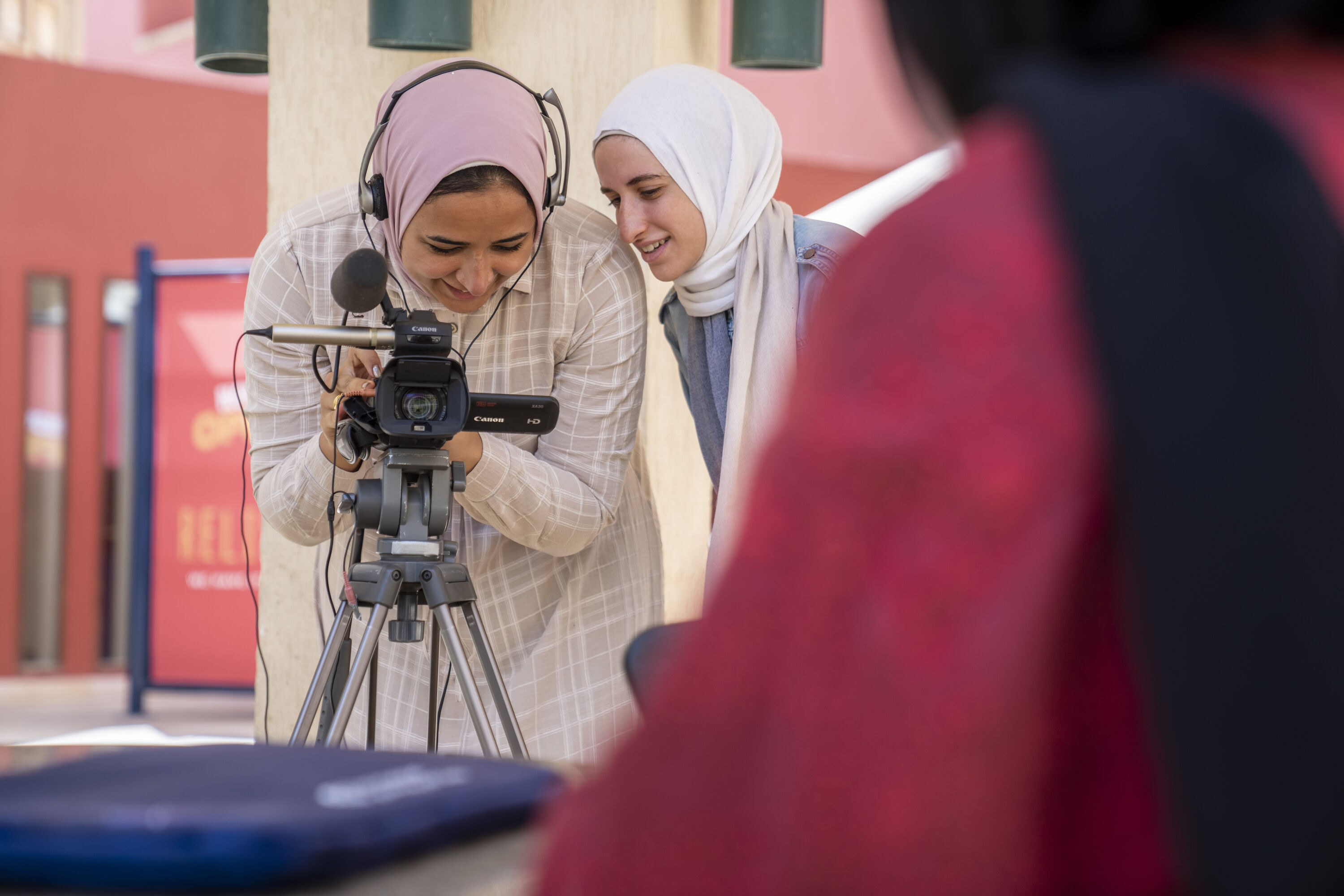 Two veiled girls looking into a video camera and smiling while filming outdoors