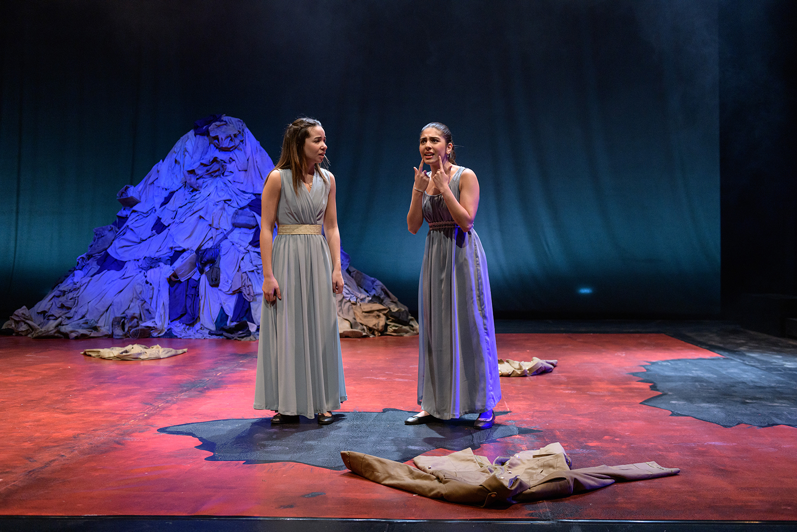 Two girls wearing long grey dresses acting on stage