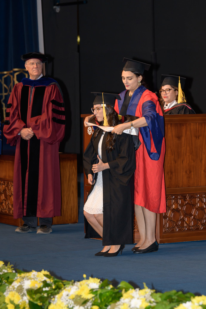 Chair of ECLT hooding a graduate student on stage  