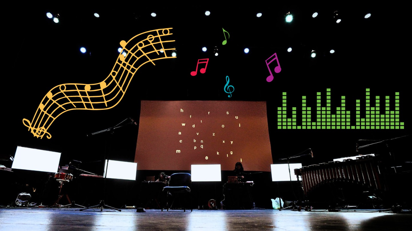 A stage with ultiple computer screens and a projected screen with assorted letters in white text, graphic overlayed shows musical notes in multiple different colors