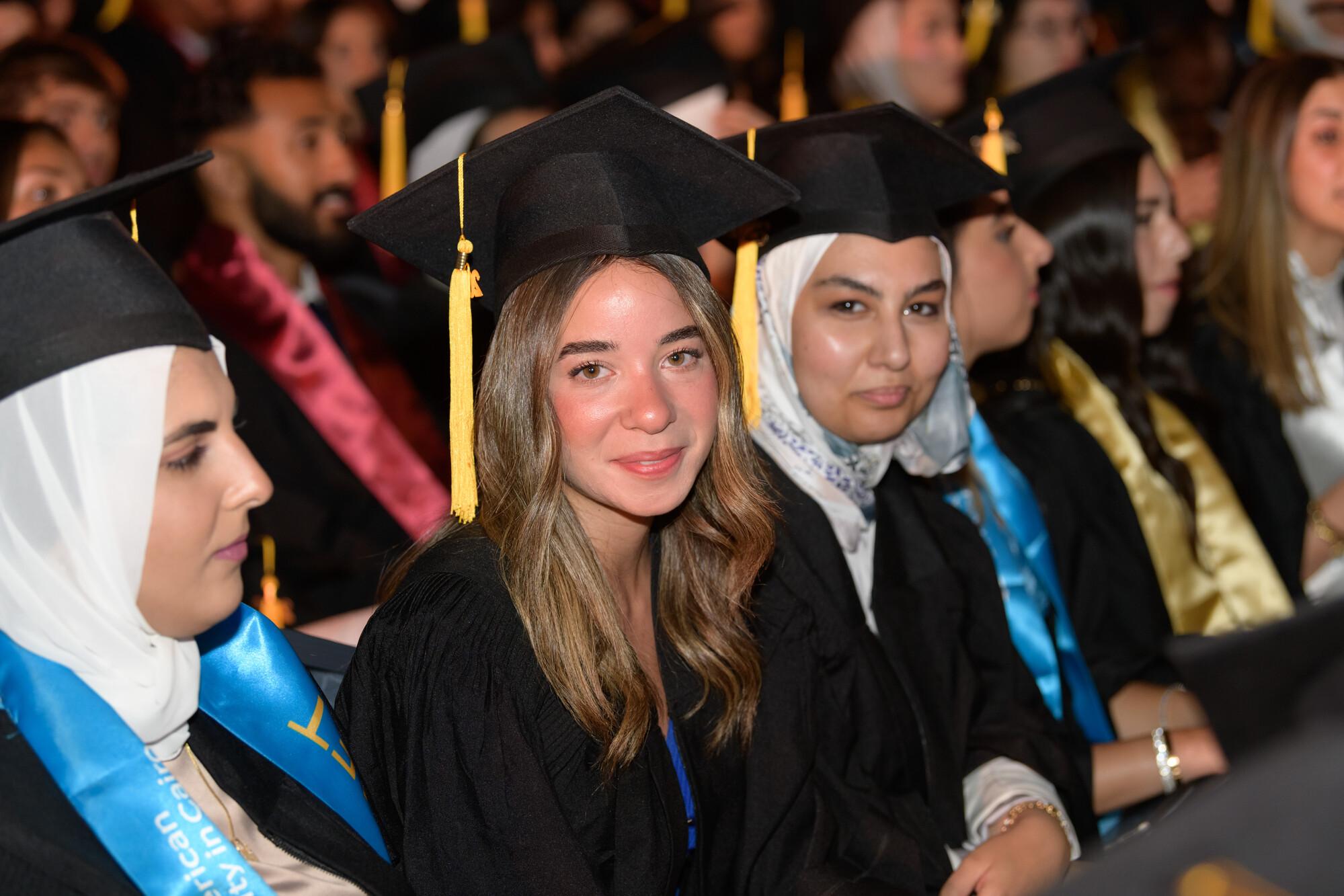 smiling students in commencement wearing cap and gown for their graduation