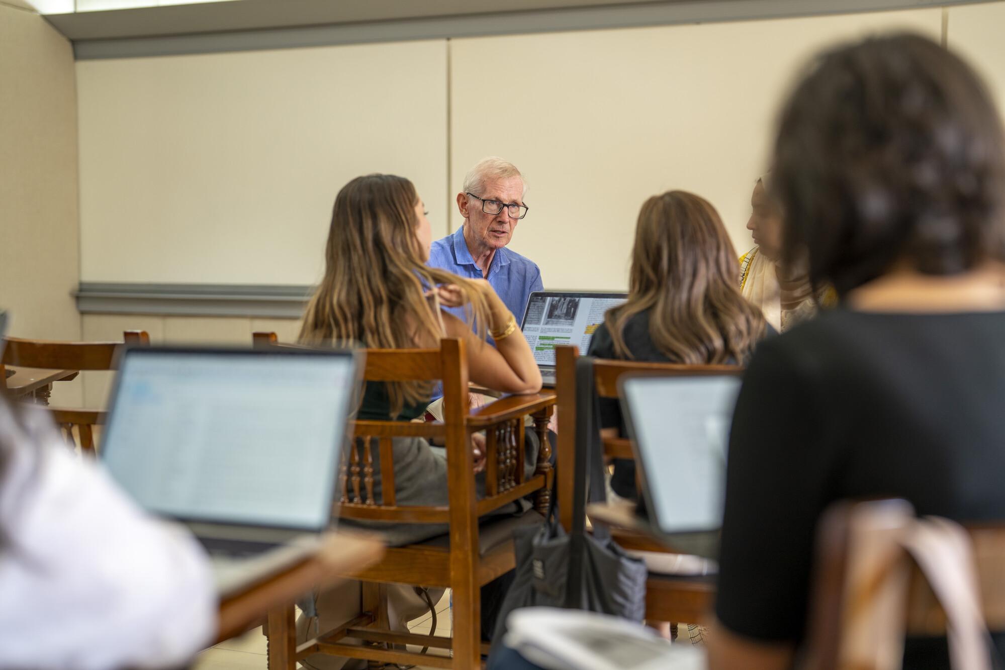 Professor Bernard O'Kane sitting with four students in a lecture setting 