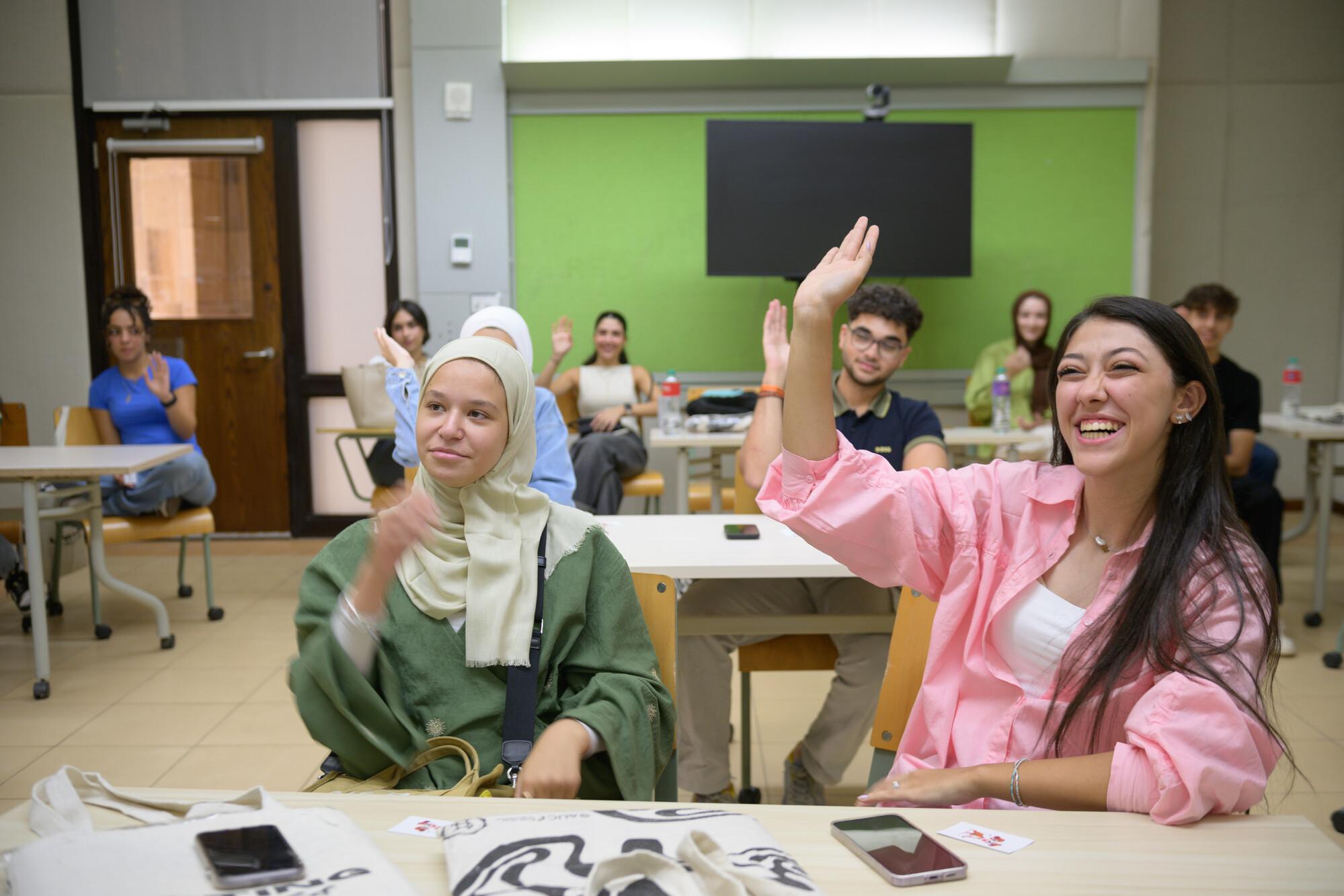 smiling students raising their hands in class