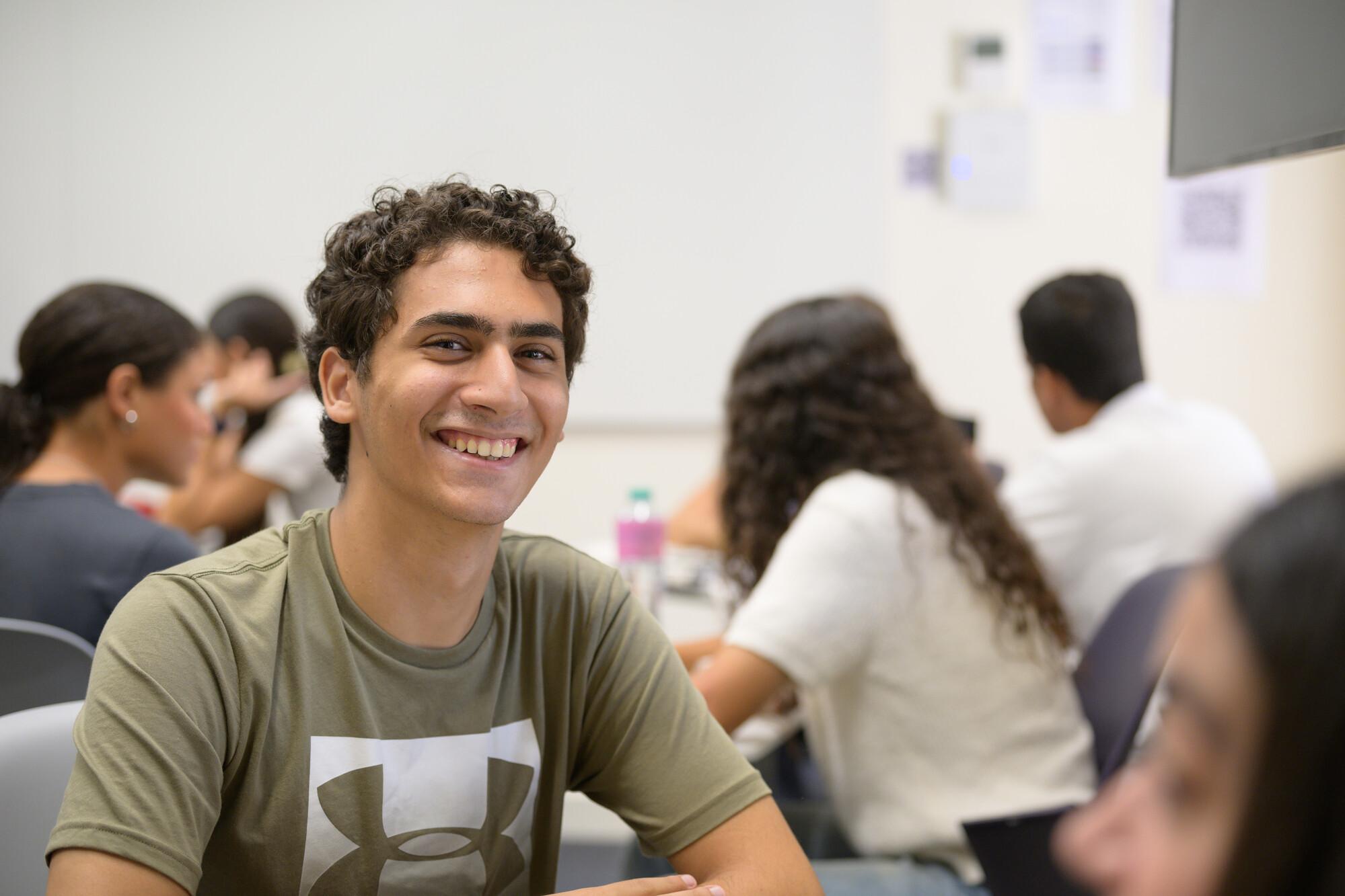 male student in class smiling whilst in class discussion