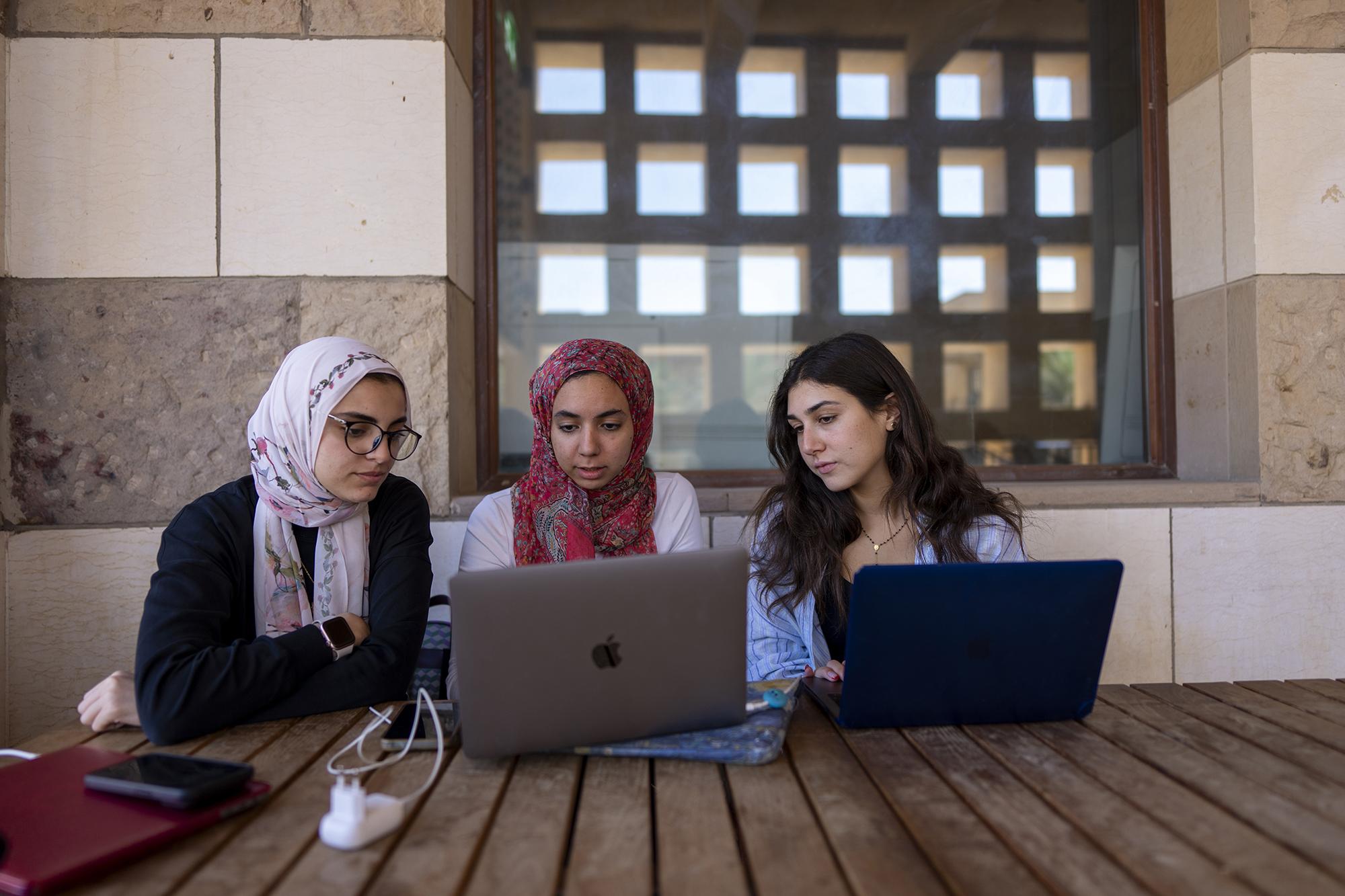 students using laptops and working on a project outside the class on campus
