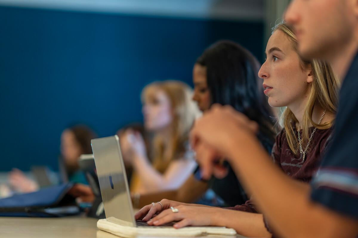 group of students in class taking notes on laptops