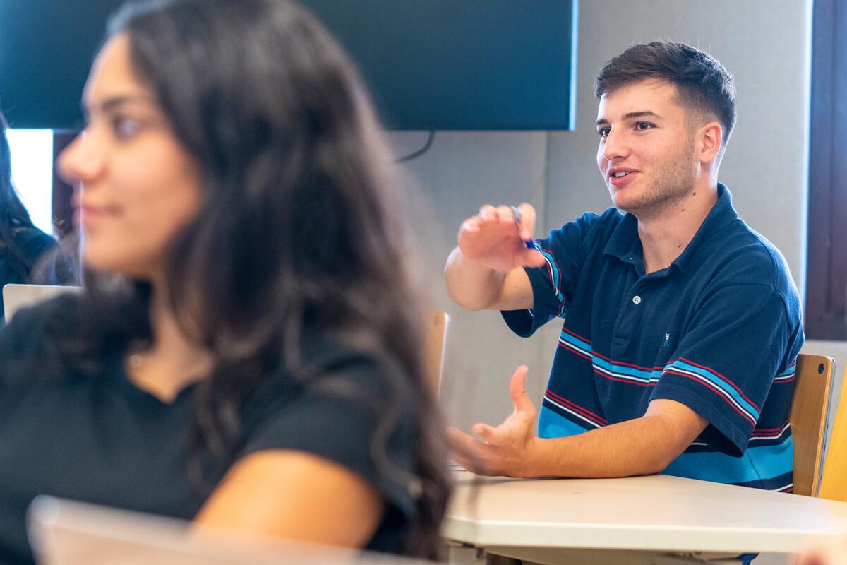 group of students in class asking questions and interacting with professor