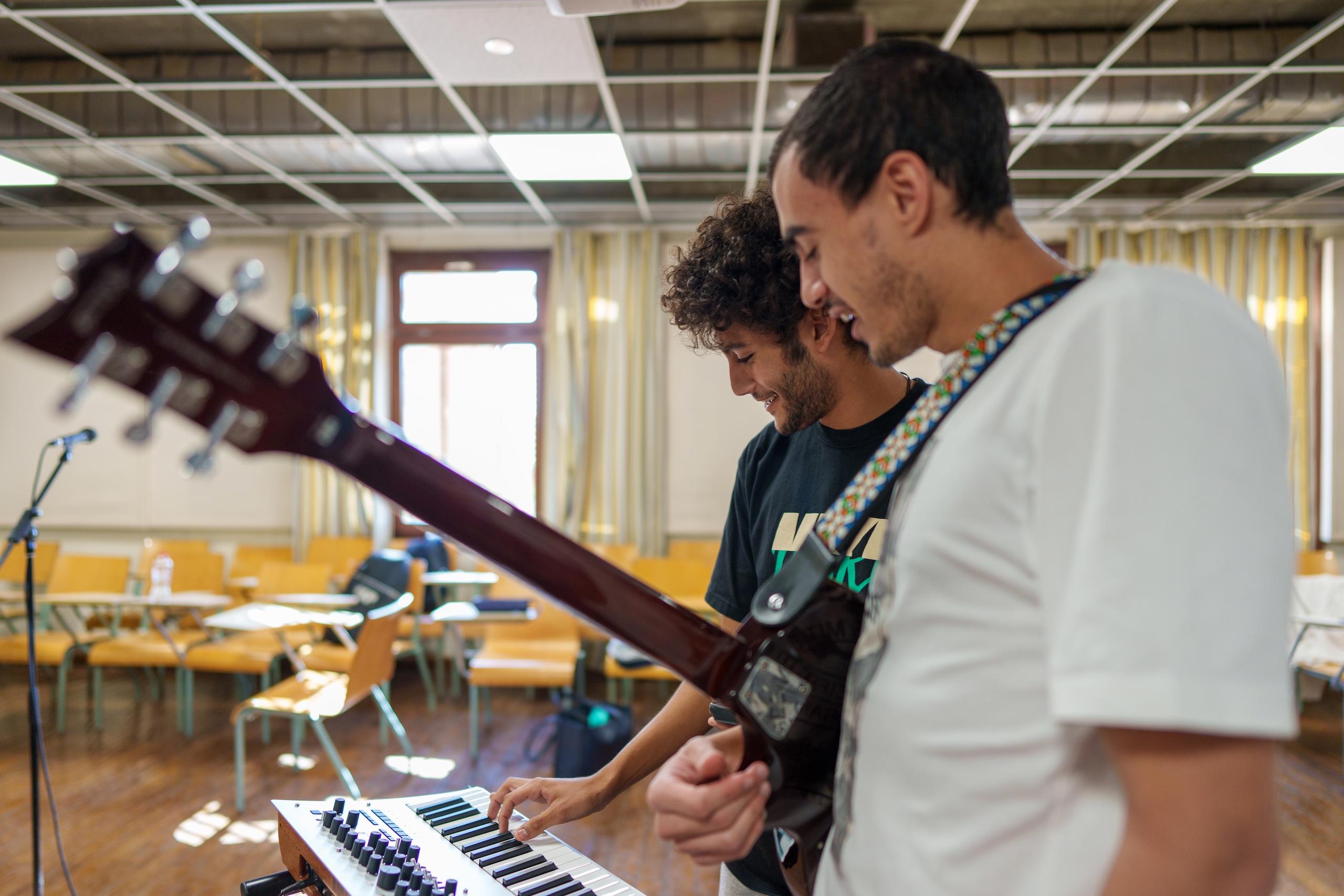 two male students in a classroom playing musical instruments