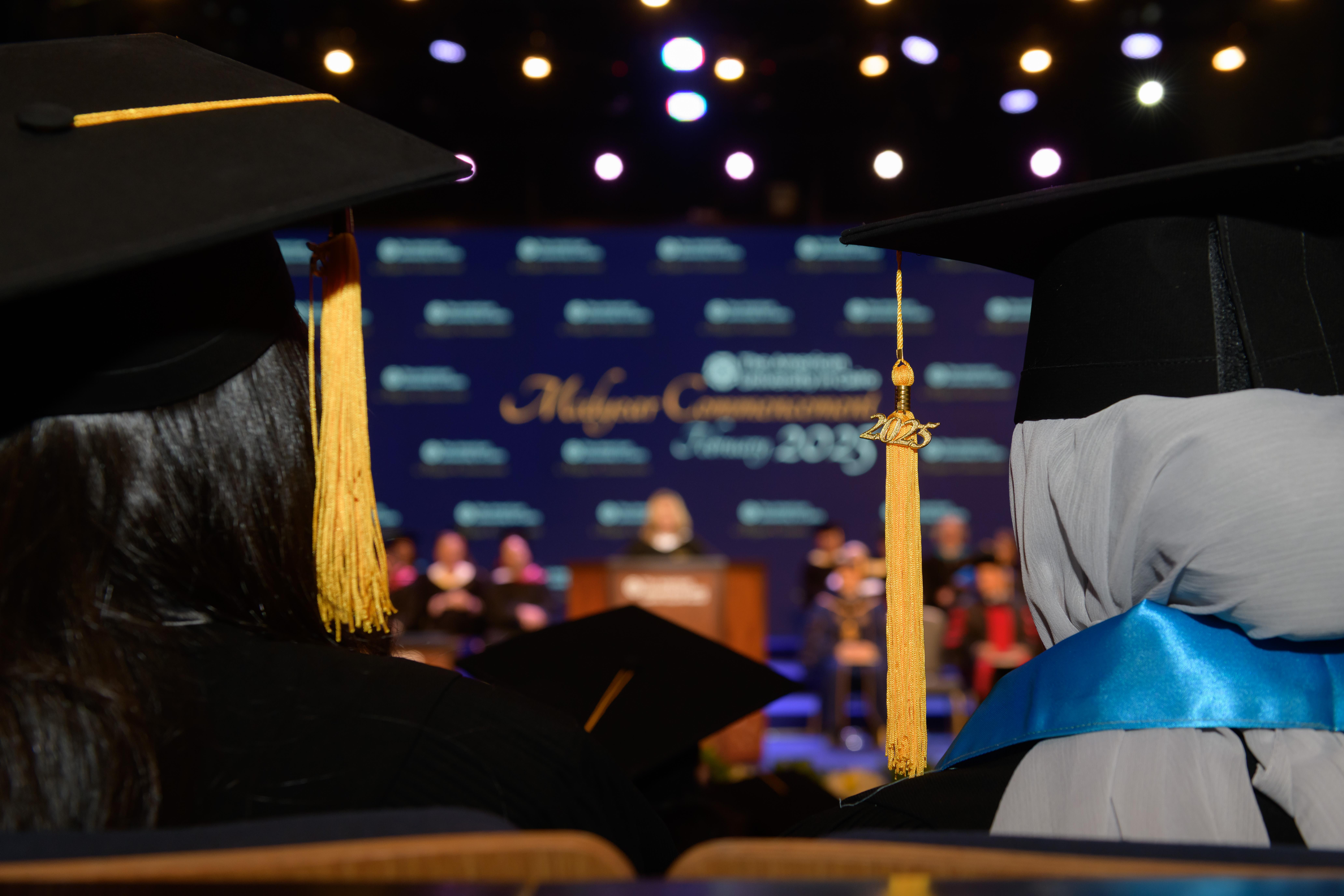 showing the two of teh graduates and teh stage is in the background