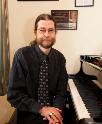 Bearded man sitting by the piano