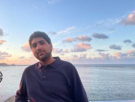 A male is standing by the sea