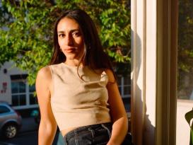 A female is sitting and leaning on a window