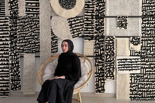 Mariem Abutaleb sits in front of her artwork