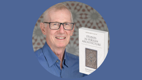 Man in a blue shirt and glasses with a book cover that reads "Studies in Persian Architecture"