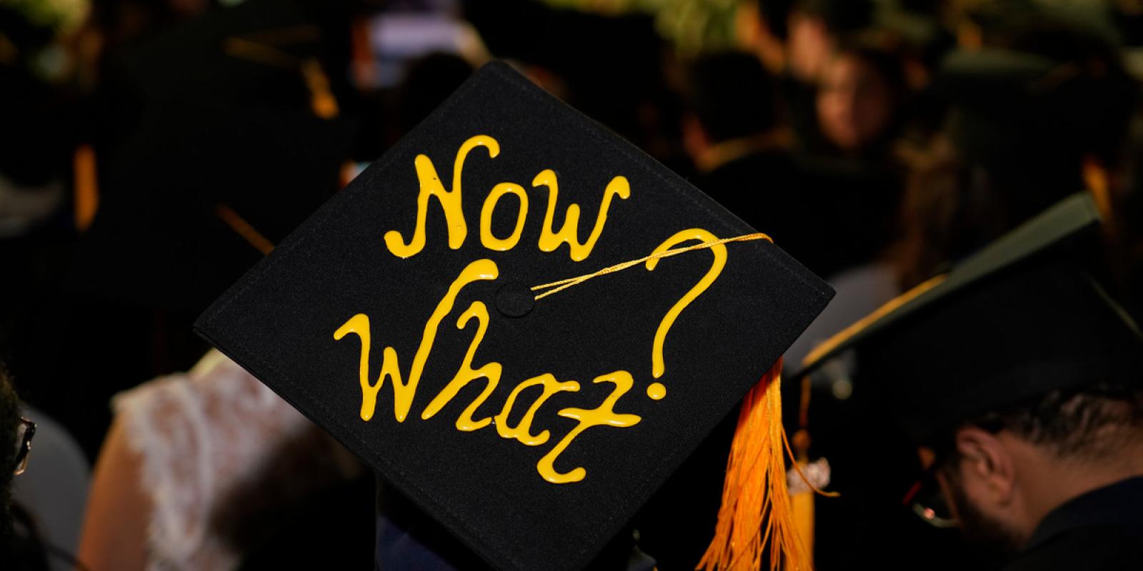 text written on cap of graduation "Now What?"