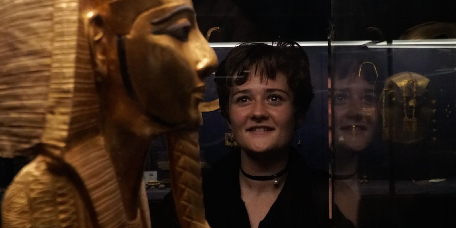 Egyptology graduate program image of student in museum looking at artifacts