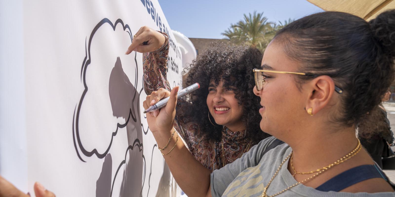 students with markers on drawing and coloring