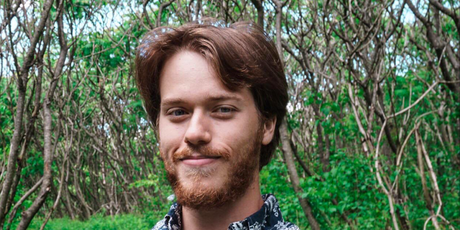 headshot of a boy with trees behind him