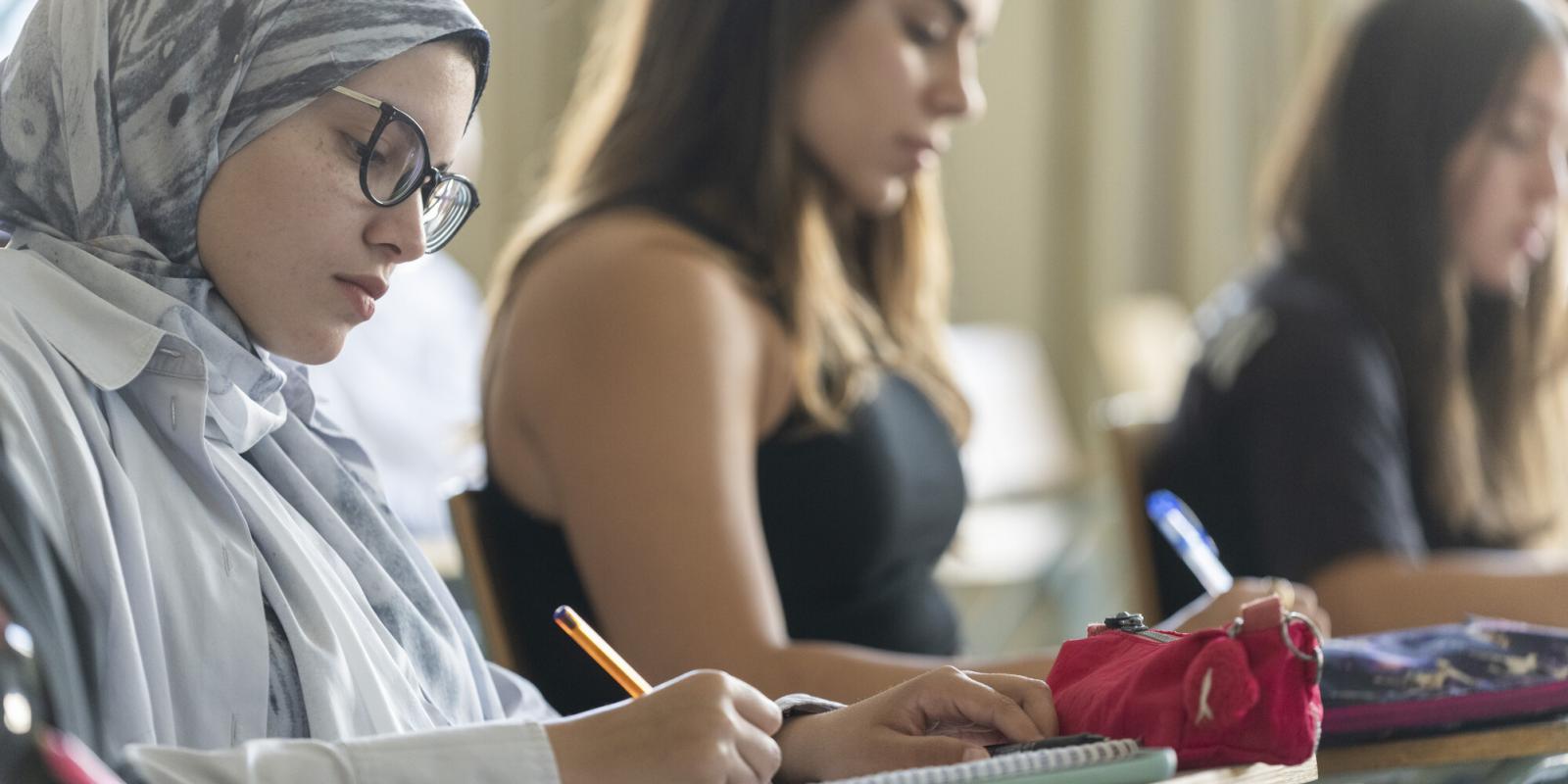 female students taking writing notes in classroom