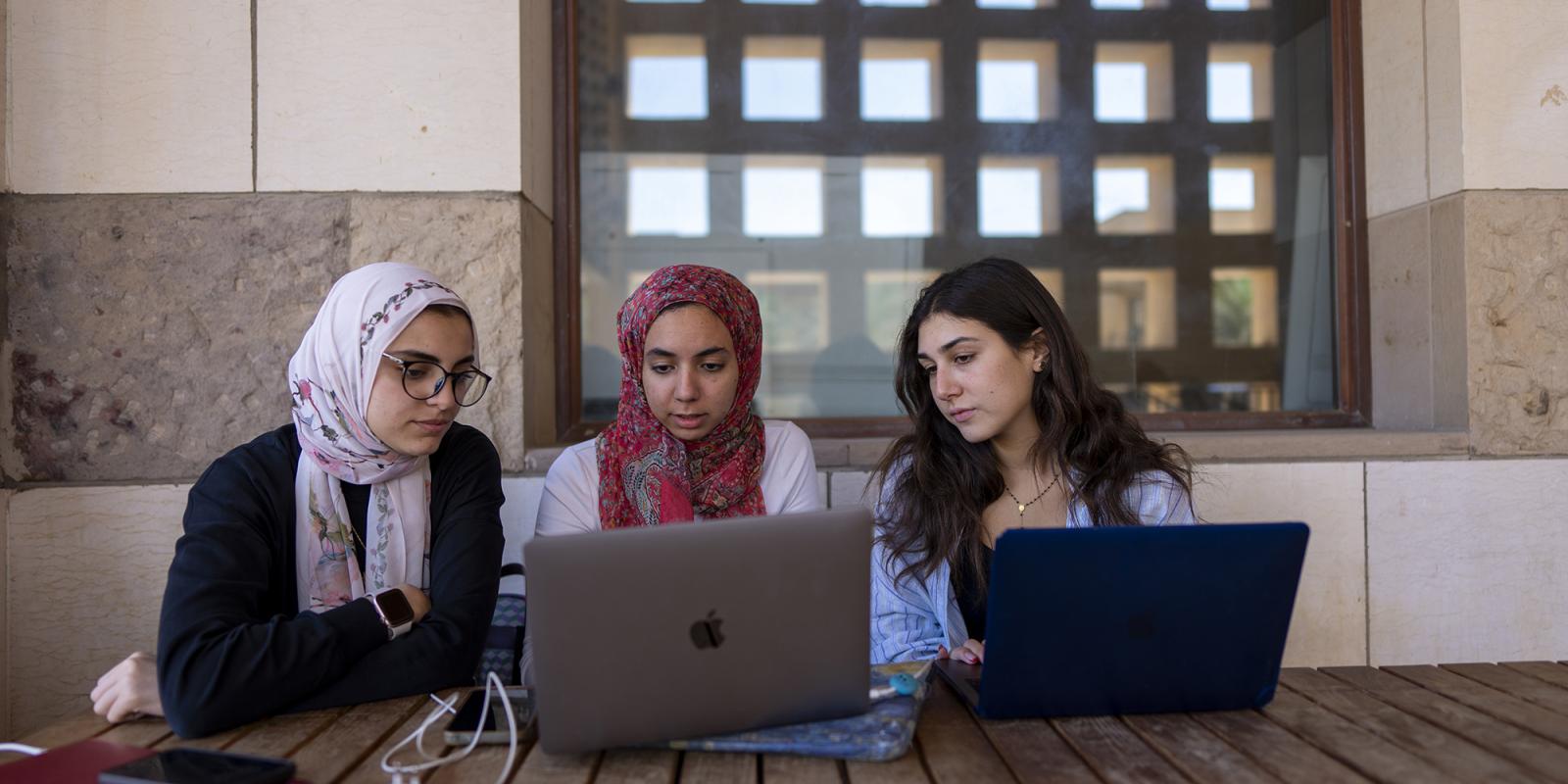 students working in laptop on a group project on a table outdoors