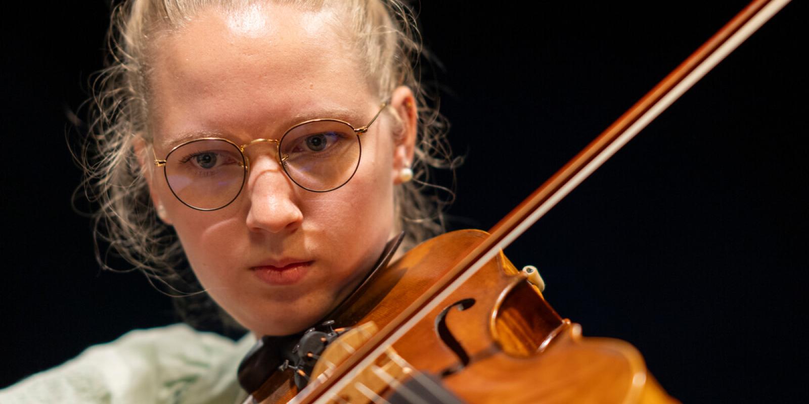 student playing the violin and focusing on the performance