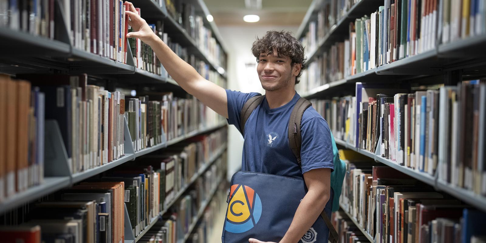 student in library selecting a book