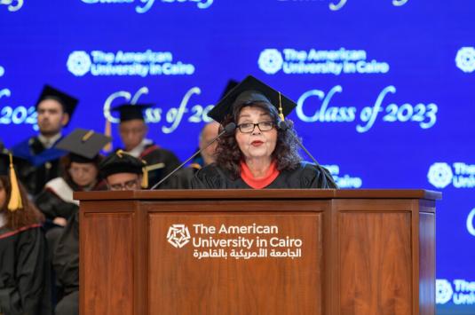 Abdel-Motaal speaks at a podium during commencement while wearing a cap and gown