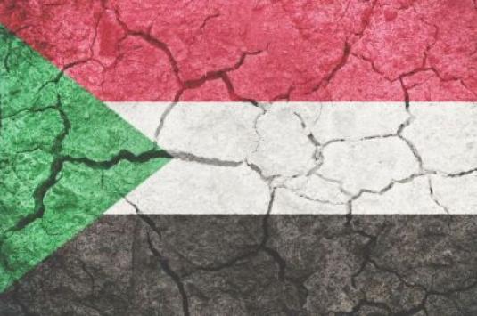 Sudan flag with cracks depicting conflict in the country