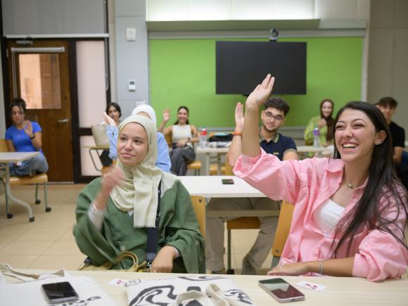 smiling students raising their hands in class