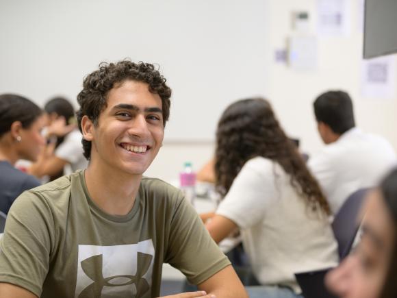 male student in class smiling whilst in class discussion