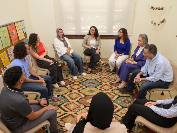 Group of students and faculty members deep in conversation while sitting in a circle