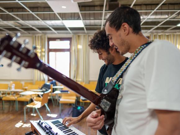 two male students in a classroom playing musical instruments